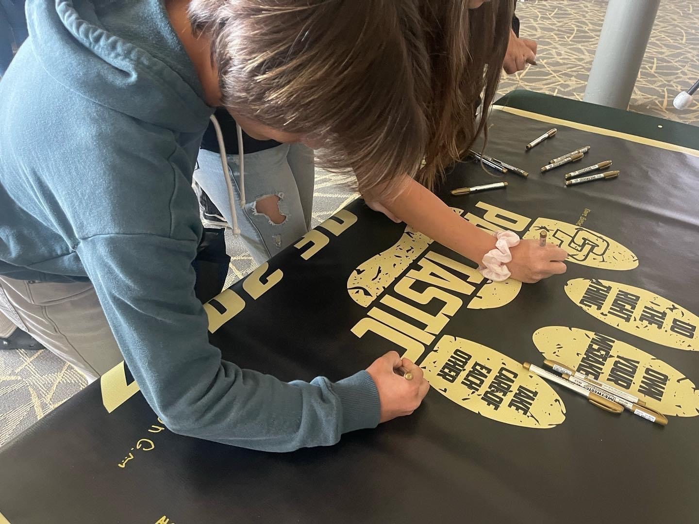 Class of 2027 students signing the Pawtastic banner.